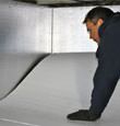 A contractor installing TerraBlock floor insulation in a Rye Brook crawl space