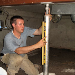 A contractor in New Canaan installing a crawl space jack post.