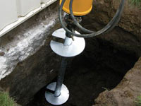 Installing a helical pier system in the earth around a foundation in Greenwich