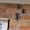 A brick wall displaying stair-step cracks and messy tuckpointing on a Greenwich home