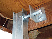 Securing the i-beam system to the top of the floor joist in a foundation wall repair in Trumbull.