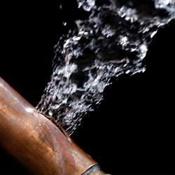 A bursting copper pipe in Greenwich, with water gushing out.