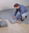 Contractors installing basement subfloor tiles and matting on a concrete basement floor in Hamden, Connecticut