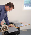 installing a waterproof vapor barrier on a basement floor to prepare for basement carpeting in a Greenwich home
